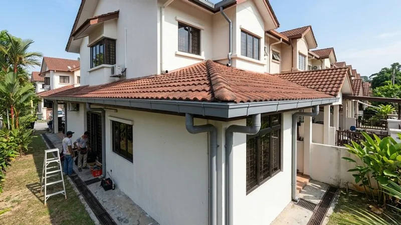 Completed seamless aluminium gutter installation on a double-storey Malaysian terrace house with neat downpipe connections