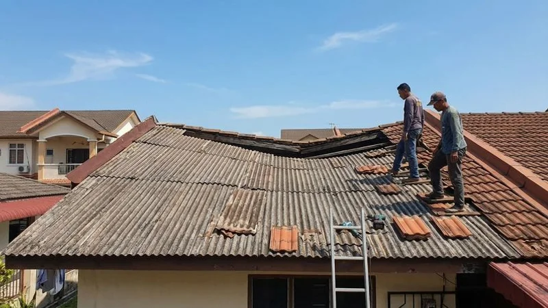 Side view of a Malaysian residential roof showing visible sagging and uneven ridge line indicating structural deterioration